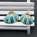 Detailed view of turquoise blue scallop pendants with golden edges for DIY jewelry making - Teal