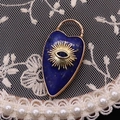 Close-up of heart-shaped lapis lazuli pendant with evil eye motif on lace fabric - Lapis Lazuli