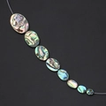 Macro detail of natural abalone shell beads with iridescent glow on a diagonal strand - Oval 6x8mm