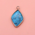Detailed macro shot of a diamond-shaped turquoise pendant with gold-plated metal edging - 15x26mm / Blue Turquoise