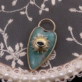 Detailed close-up of a heart-shaped turquoise stone pendant with golden evil eye sunburst - Amazonite