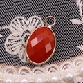 Macro detail of oval faceted red gemstone pendant with gold plated edge on lace background - 11x19mm / Red Jasper