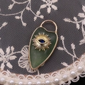 Shield-shaped green agate evil eye pendant with golden sunburst and blue gemstone detail - Green Aventurine