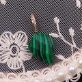 Macro d'un pendentif en malachite facettée avec bélière dorée et détails de dentelle - Malachite