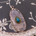 Macro shot of oval pink crystal pendant with blue turquoise inlay on white lace fabric - 16x36mm, 4g / Rose Quartz