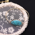 Primer plano del brazalete ajustable dorado con piedra turquesa ovalada sobre encaje - Turquesa Azul