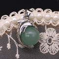 Macro shot of dolphin pendant with green gemstone on white lace floral background - 14x23mm / Green Aventurine