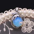 Makroaufnahme von Delfinanhänger aus Silber mit blauem Mondstein auf Spitze - 14x23mm / Opal