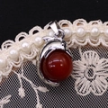 Detailansicht des silbernen Delphinanhängers mit einer roten Karneolperle auf Spitze - 14x23mm / Roter Achat