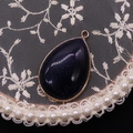 Blue sandstone teardrop pendant with gold metal edging on a white lace background - Blue Sandstone
