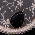 Waterdrop-shaped black tiger eye stone pendant with gold plated rim on lace background - Black Agate