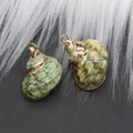 Natural sea shell pendants with gold plated alloy loops on a dark grey surface - Style 31