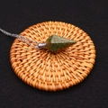 Detailed macro of unakite crystal perfume bottle pendant with silver chain on woven mat - Unakite