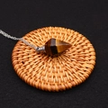 Macro shot of tiger eye stone crystal perfume bottle pendant on rustic rattan coaster - Tiger's Eye