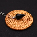 Macro shot of obsidian hexagonal prism pendant with silver chain on a woven mat - Black Agate