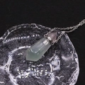 Close-up of a green crystal perfume bottle pendant with a pink tip and silver chain - Fluorite