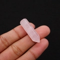 Hand holding a natural polished rose quartz hexagonal point crystal with pink hues - 8x33mm / Rose Quartz