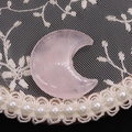 Close-up of crescent-shaped natural rose quartz stone on white lace embroidery with pearls - 25x30mm, 8mm Thickness / Rose Quartz