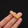 Macro detail of natural yellow hexagonal stone crystal point held between fingers - 8x33mm / Topaz
