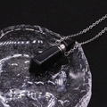 Macro shot of a black obsidian hexagonal prism perfume bottle pendant with silver chain - Black Agate