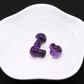 Macro shot of three purple mushroom-shaped dragon vein agate beads on a white ceramic bowl - Purple