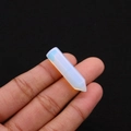 Close-up of a translucent opalite hexagonal prism crystal held in a person's hand - 8x33mm / Opal