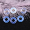 Vista macro di perle donut in opalite blu e piuma viola su velluto nero elegante - 16mm, Foro 6mm / Opale