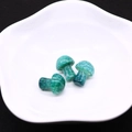 Macro shot of three mushroom-shaped green dragon vein agate beads on a white plate - Emerald Green
