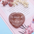 Vista macro de una piedra de pulgar de cuarzo fresa en forma de corazón sobre tarjeta - Cuarzo Fresa