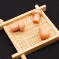 Trois figurines champignons en pierre orange avec texture blanche sur un plateau en bambou - Calcite Orange