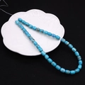 Close-up of 8x10mm blue turquoise drum beads for jewelry making on a white petal plate - Barrel Beads / No. 12 (Sky Blue Mesh)