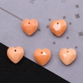 Macro view of five faceted orange-pink heart-shaped natural stone pendants with top holes - Orange Carnelian