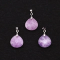 Detailed macro view of three faceted purple natural stone teardrop pendants on black fabric - Phosphosiderite