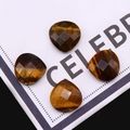 Macro-opname van vier gefacetteerde hartvormige tijgeroog kralen voor DIY sieraden - Tijgeroog