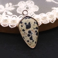 Détail d'un pendentif en jaspe dalmatien avec bordure dorée sur un plateau en perles - Jaspe dalmatien