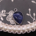 Macro view of blue teardrop natural stone pendant with silver metal bezel and bail - Blue Sodalite