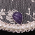 Macro shot of purple teardrop crystal pendant with silver metal edge and ring - Purple Crystal