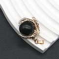 Vista detallada de un colgante de garra de dragón dorado con una esfera de piedra negra - 25x31mm, 15g / Howlita de Línea Negra