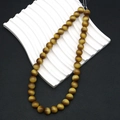 Close-up of brown tiger eye beads on white wave stand and black leather background - Golden Brown (No.6)