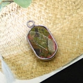 Macro view of oval natural picture jasper pendant with silver plated metal border - Unakite