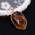 Macro detail of hexagonal tiger eye stone pendant with gold plated bezel and bail - Tiger's Eye
