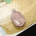 Oval rose quartz pendant with silver-plated edge on a textured woven background - Rose Quartz