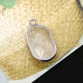 Oval silver-plated pendant featuring pink stone with star facets on natural texture - White Crystal