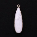 Macro shot of long teardrop turquoise pendant with gold plated edges on black velvet - 11x41mm / Howlite