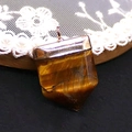 Macro shot of tiger eye stone pendant with rose gold plating on a lace background - 20x30mm / Tiger's Eye
