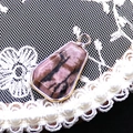 Primo piano del ciondolo trapezoidale in rodonite placcato oro con pizzo vintage - Rodonite
