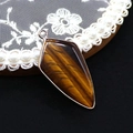 Macro detail of a shield-shaped tiger eye stone pendant with polished metallic edge - Pendant Only (No Chain) / Tiger's Eye