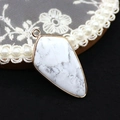 Macro shot of shield-shaped howlite pendant with gold plated trim on lace tray - Pendant Only (No Chain) / Howlite
