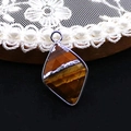Macro shot of rhombus-cut tiger eye stone pendant with silver metal edging and inlay - Tiger's Eye