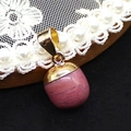 Anhänger aus rosa Edelstein in Tropfenform mit goldener Öse auf Holzständer - Roter Holzmaserungsstein
